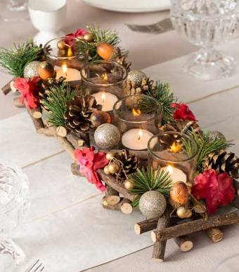 centro de mesa feito com pinhas, troncos, flores do natal e velas